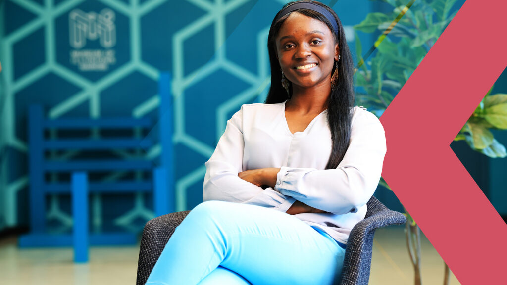Operations Manager at Museum of Illusions Nairobi seated inside the venue with branded décor in the background
